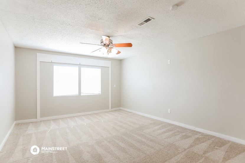 an empty room with a ceiling fan and a window