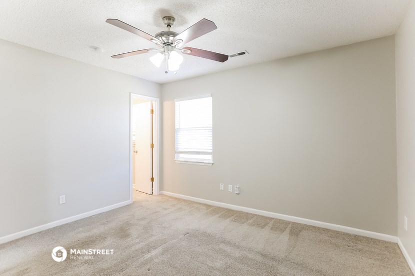 an empty living room with a ceiling fan and a window