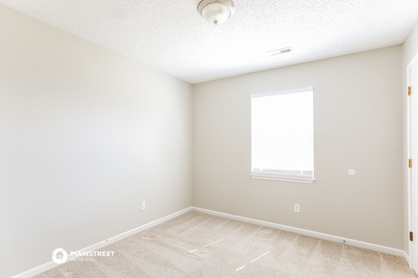 an empty room with a window and white walls