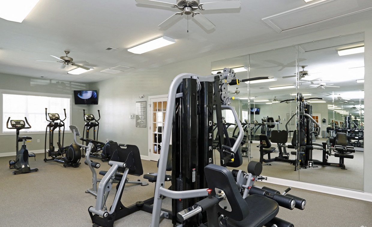 a gym with various exercise equipment and a ceiling fan