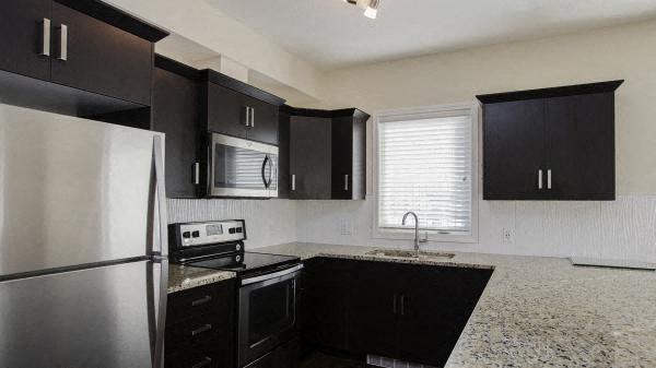 a kitchen with black cabinets and a stainless steel refrigerator