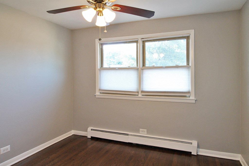 an empty room with a window and a ceiling fan