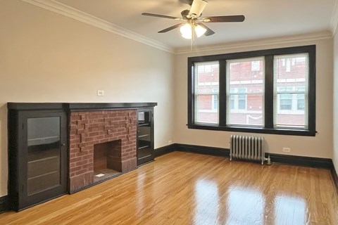 A living room with a fireplace and a ceiling fan.