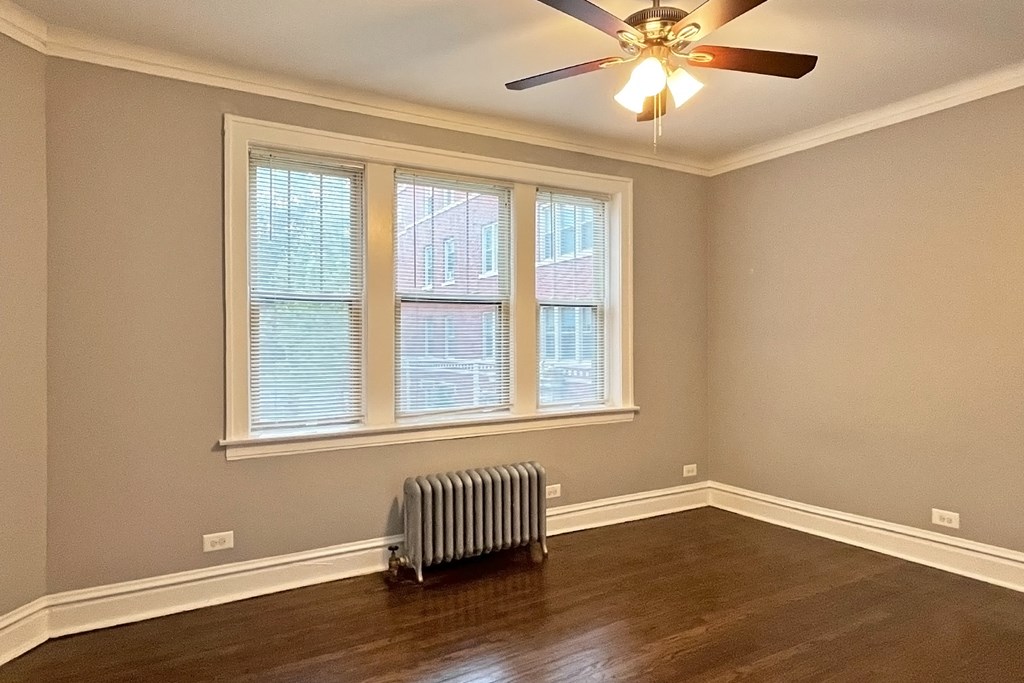A room with a ceiling fan and a window with blinds.