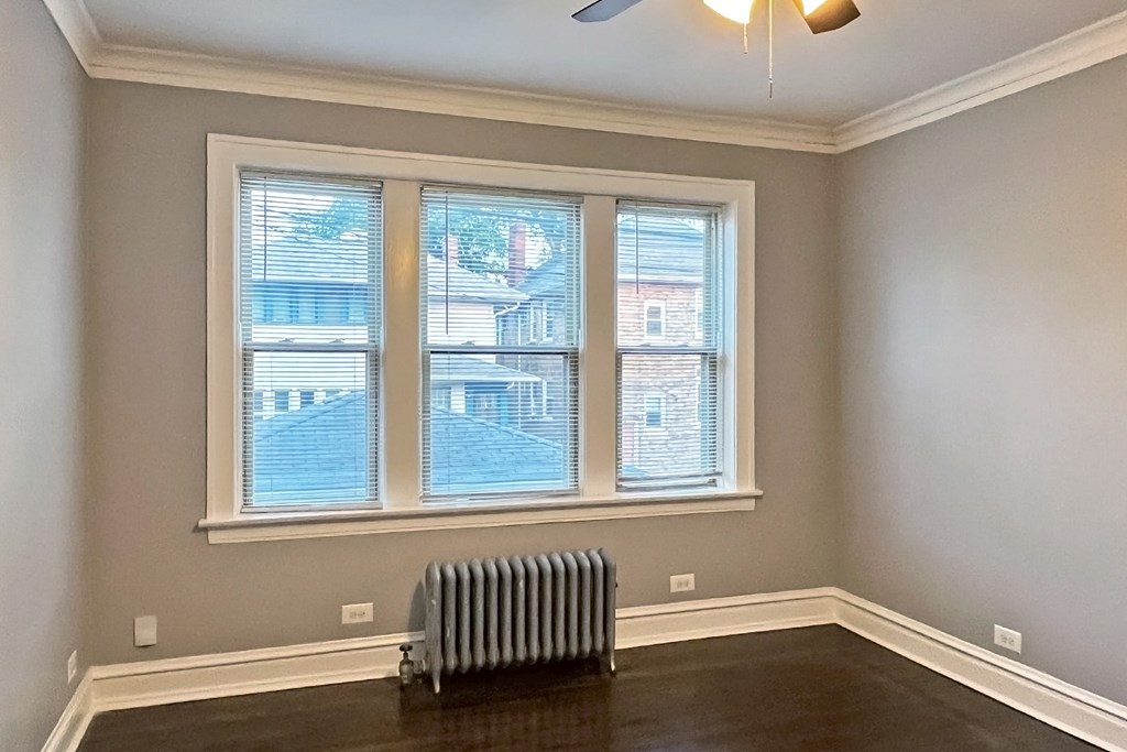 A room with a window and a radiator on the floor.