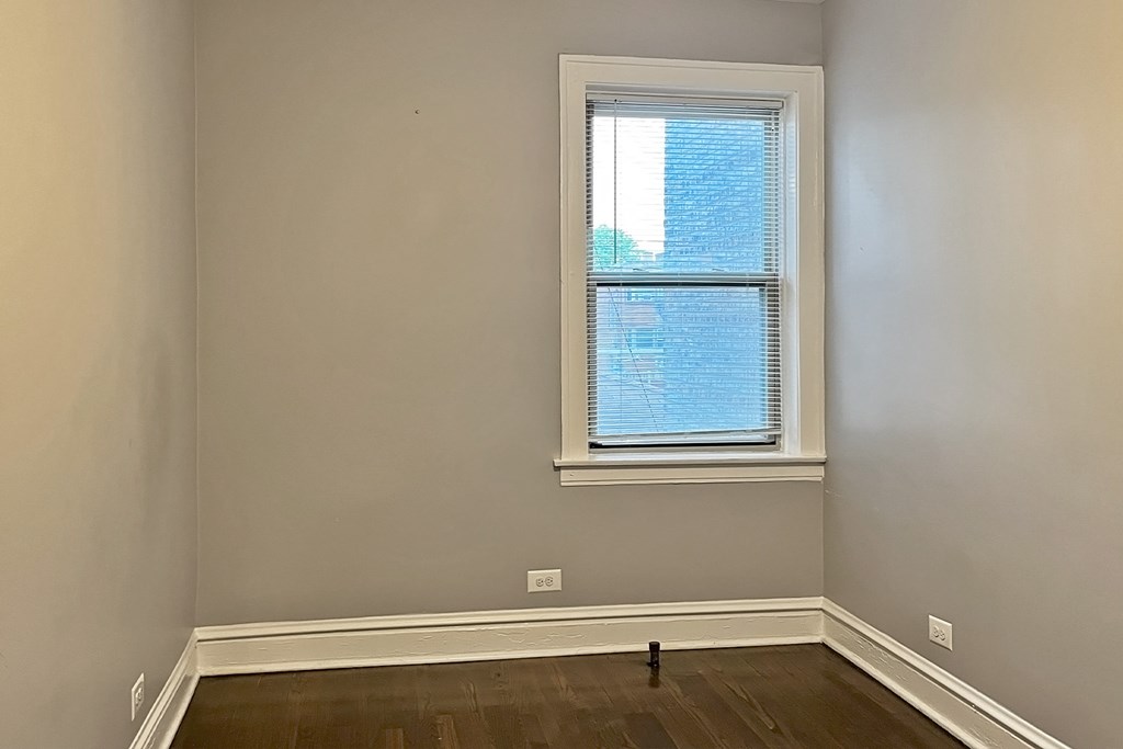 A room with a window and wooden flooring.