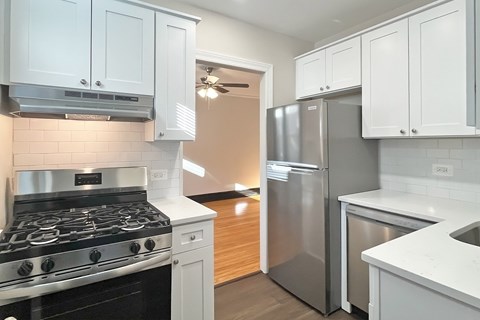 A kitchen with a stove, refrigerator, and cabinets.