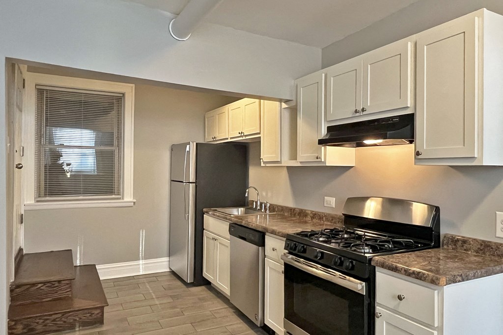 A kitchen with a black stove top oven and white cabinets.