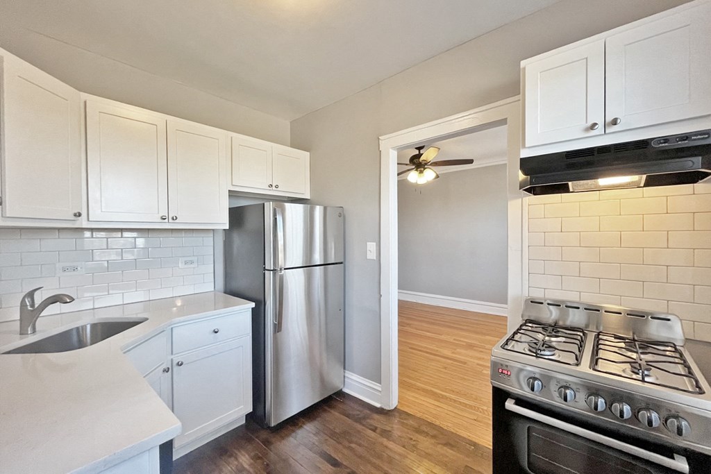 A kitchen with white cabinets and a stainless steel refrigerator.