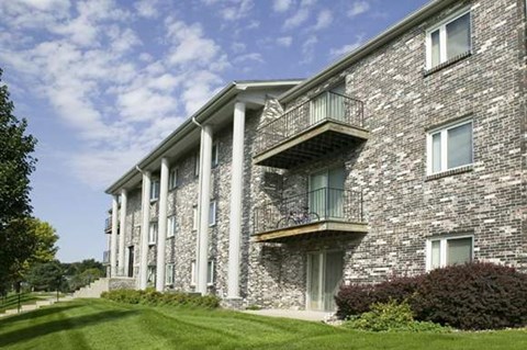 a brick apartment building with balconies and a green lawn