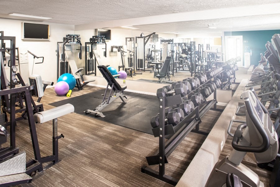 a gym with cardio equipment and weights on the floor