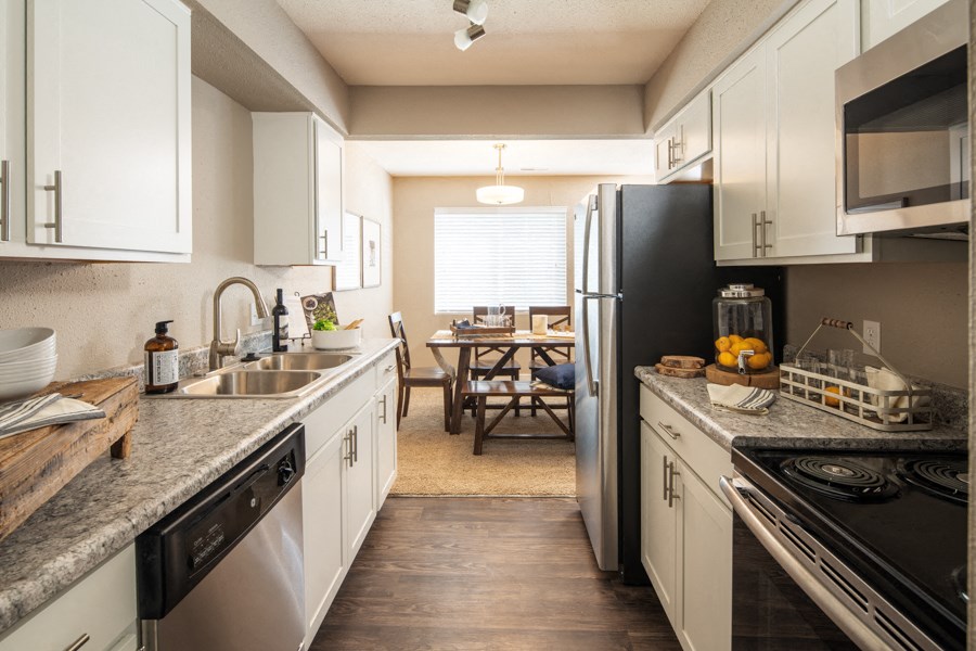 a kitchen with white cabinets and granite counter tops and a black refrigerator