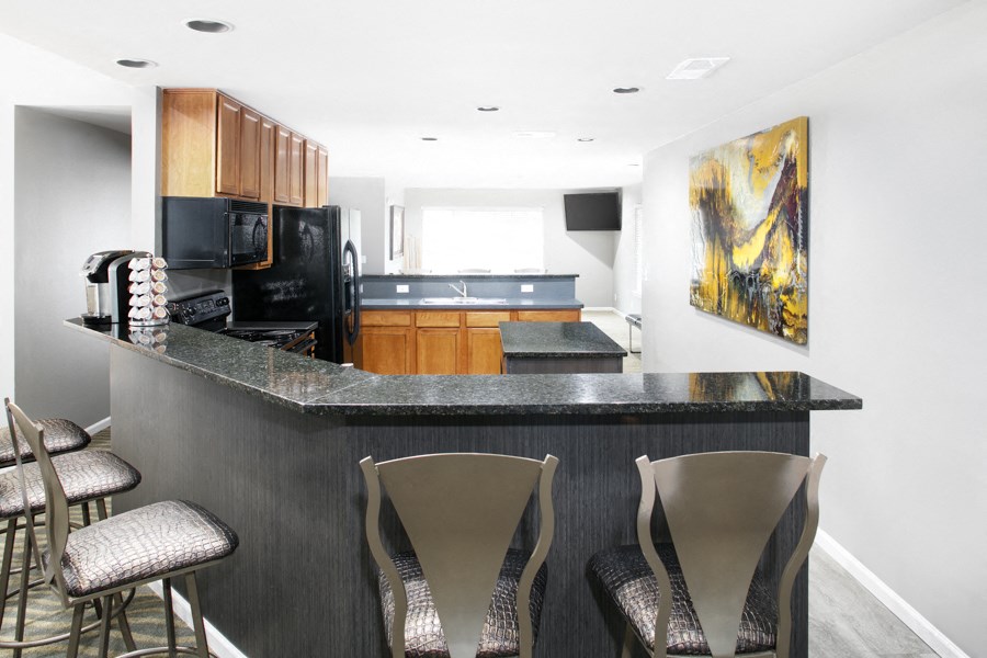 a kitchen with a bar with three chairs