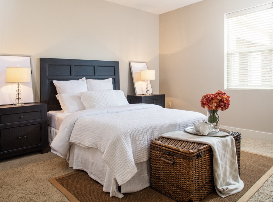 a bedroom with a bed and a table with a vase of flowers