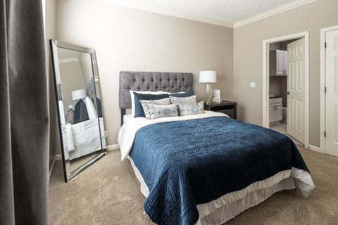 A bedroom with a large bed and a mirror on the wall.