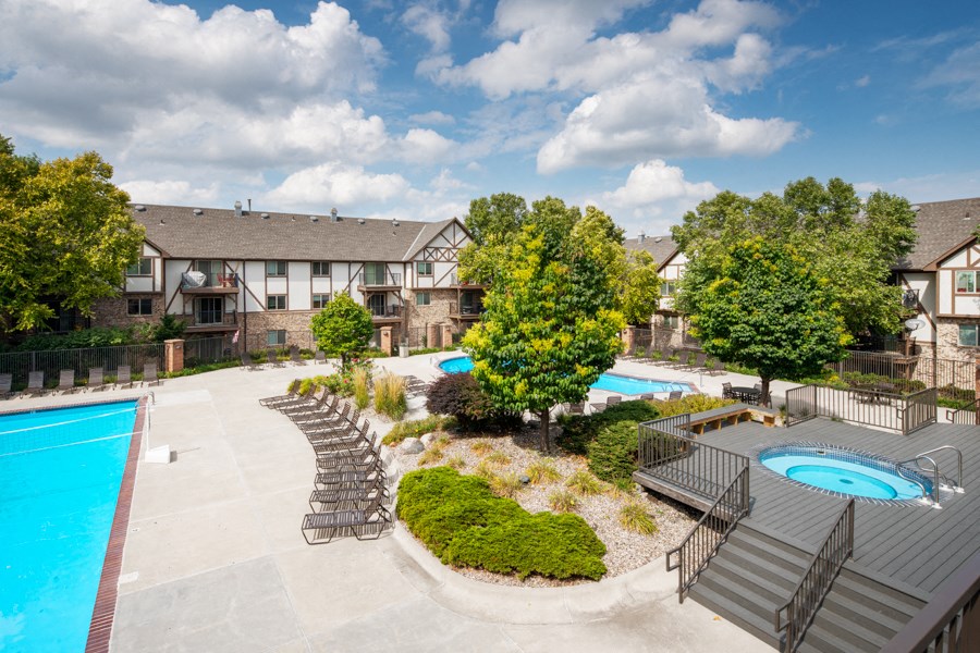an aerial view of a swimming pool and patio with chairs and trees