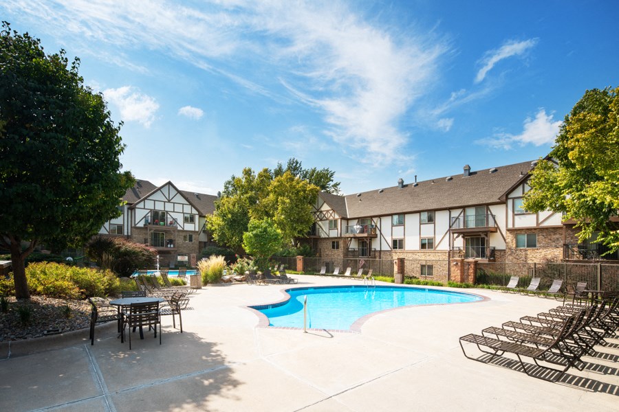 a swimming pool with chairs in front of an apartment building