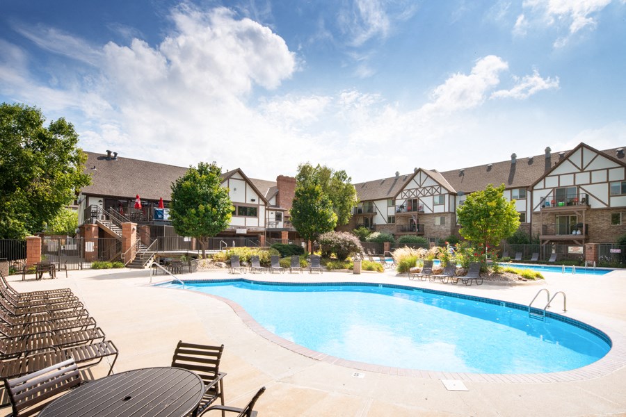 a swimming pool with chairs and buildings in the background