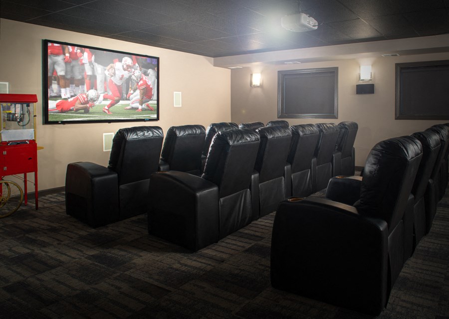 an empty theater room with black leather chairs and a movie screen