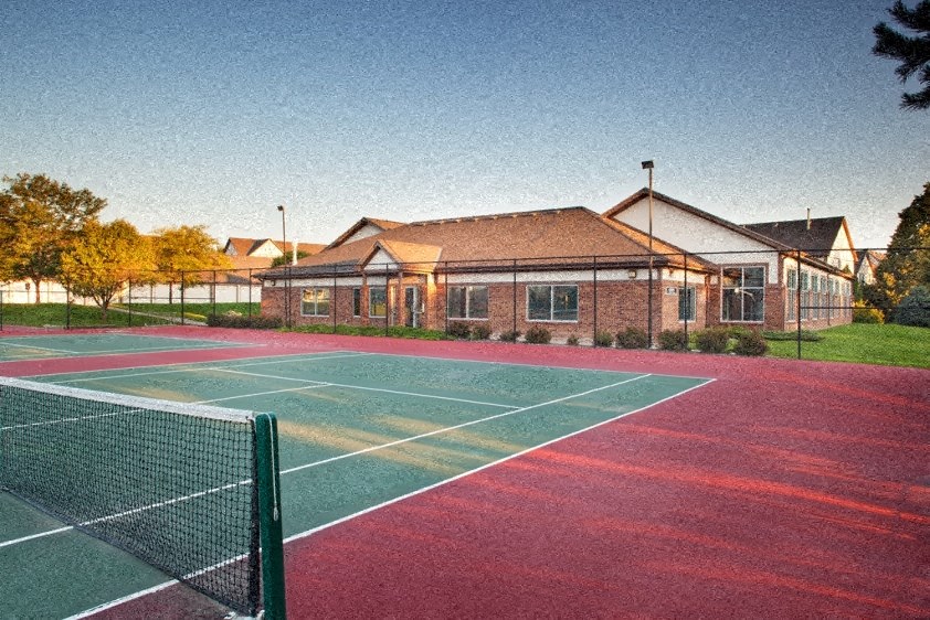 a tennis court in front of a house with a building