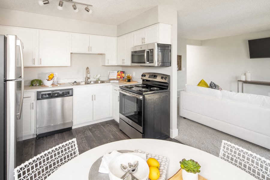 a white kitchen with stainless steel appliances and a white table