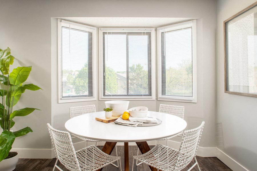 a dining room with a white table and chairs and three windows