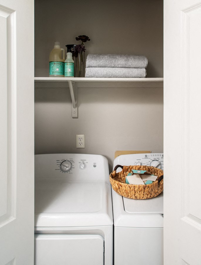 a small laundry room with a washer and dryer and a basket on top