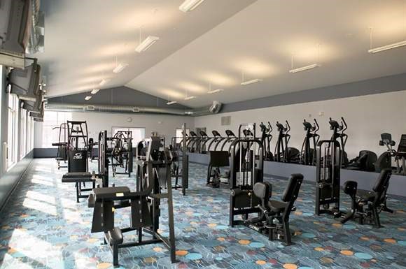a gym with rows of exercise equipment and chairs