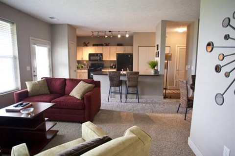 A living room with a red couch and a white wall with a decoration on it.