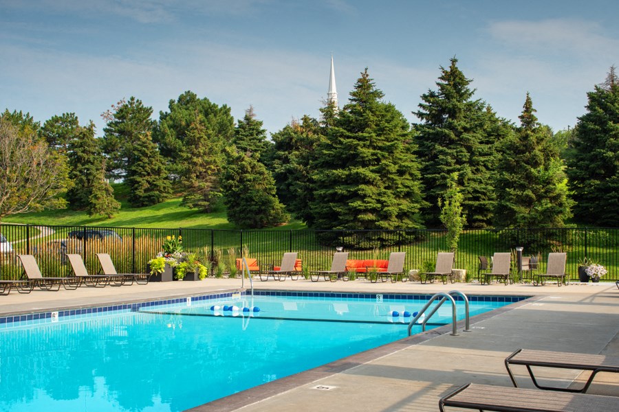 a swimming pool with chairs and trees in the background