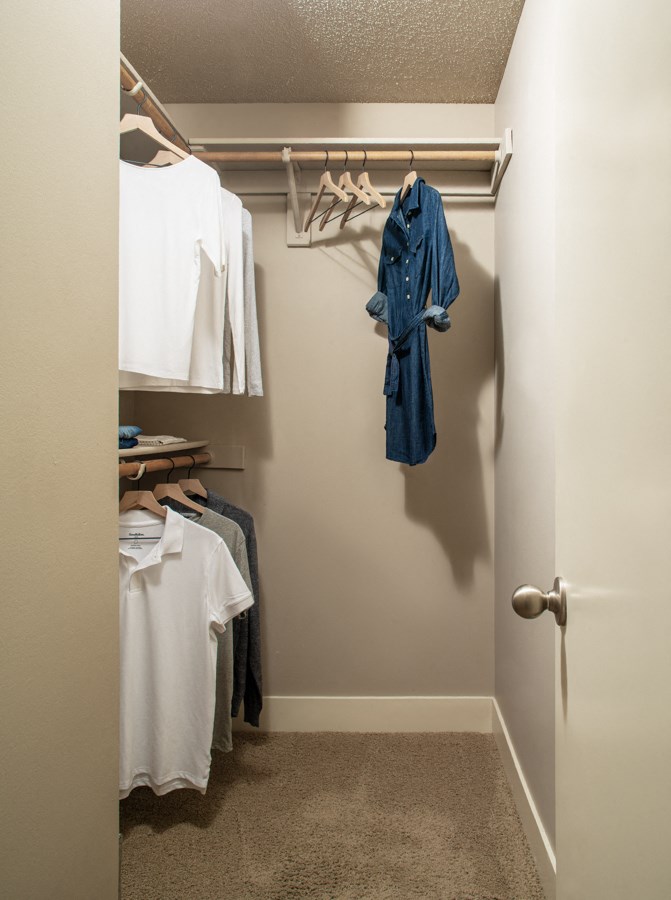 a walk in closet with a door open and clothes hanging on a rack