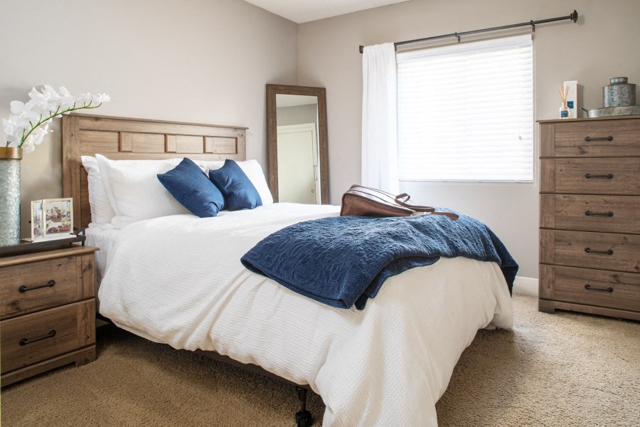 a bedroom with a bed and two dressers and a window