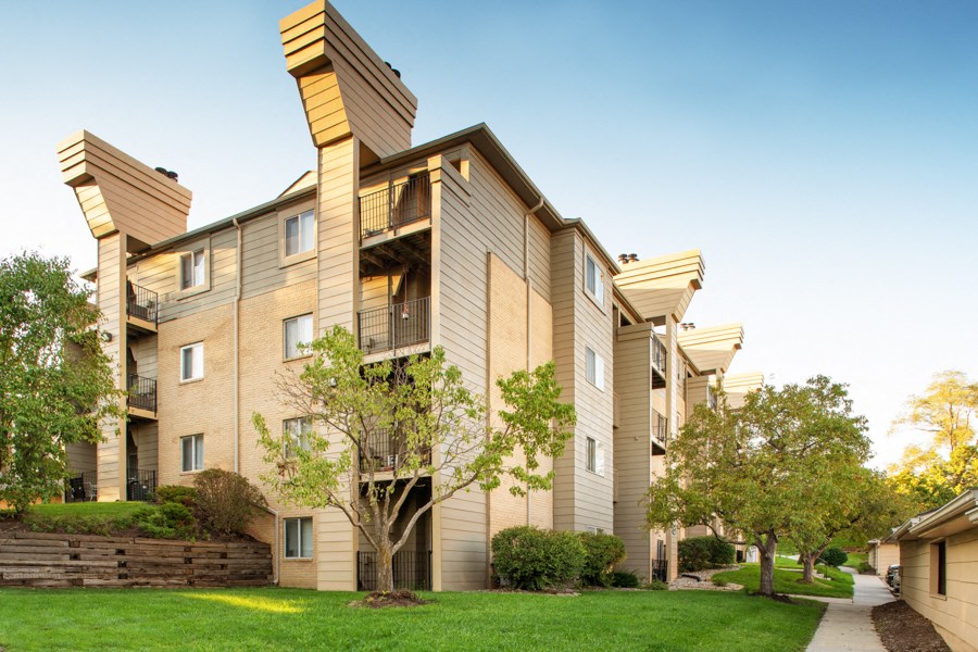 an apartment building with trees and a sidewalk
