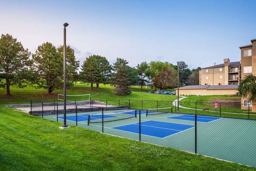 a tennis court with apartments in the background