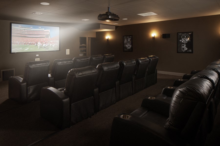 a dark screening room with leather chairs and a projection screen