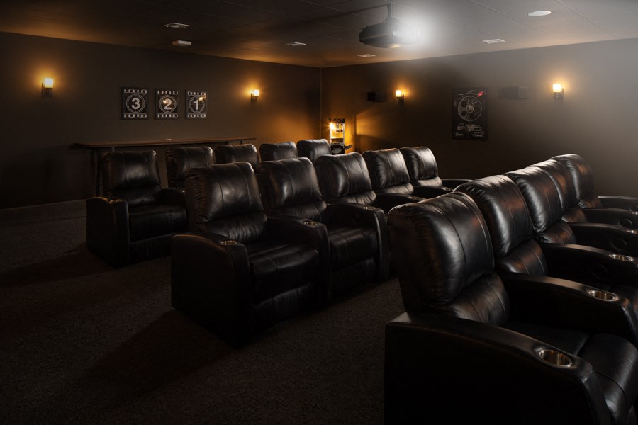 a dark room with leather chairs and a projector screen