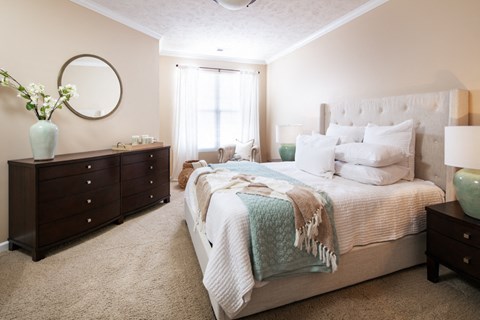 a bedroom with a bed and two dressers and a window