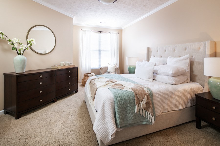 a bedroom with a bed and two dressers and a window