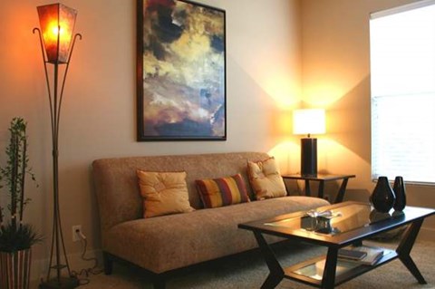 A living room with a couch, a table, and a painting on the wall.