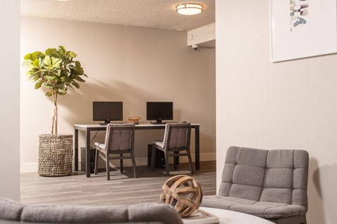 a living room with a desk with two monitors and a couch