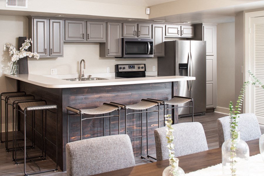a kitchen with stainless steel appliances and a counter with bar stools