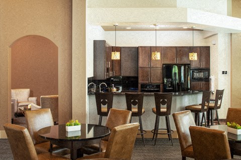 A modern kitchen with brown chairs and a black table.