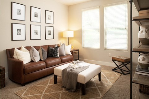A brown leather couch with a grey throw on it sits in a living room.
