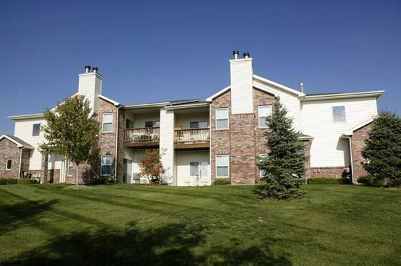 an apartment building with green grass and trees