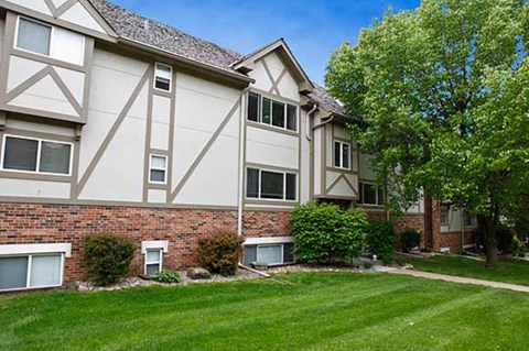an apartment building with a green lawn and trees
