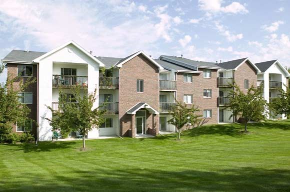 an apartment building with green grass and trees
