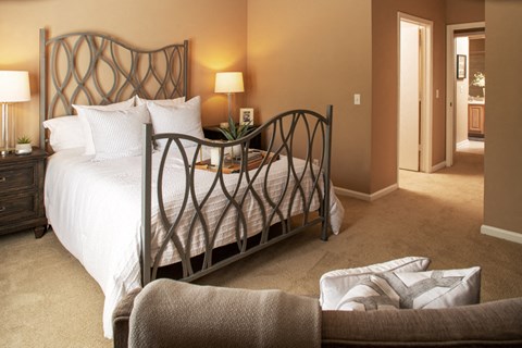 A bedroom with a large bed and a chair.