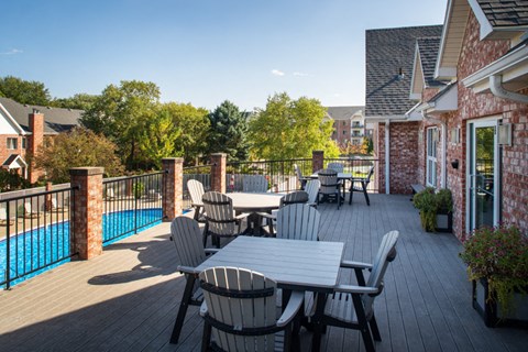 A patio with a table and chairs overlooking a pool.