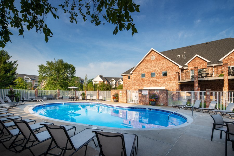 a swimming pool with chairs around it in front of a house
