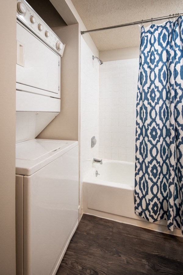 a small bathroom with a white washer and dryer and a shower and tub